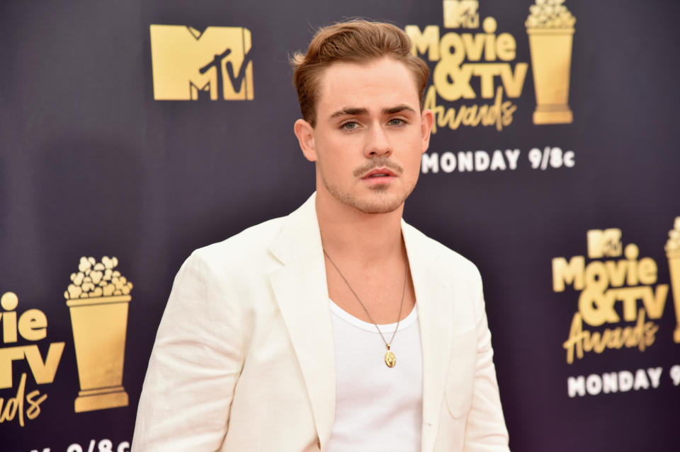 A photo of Dacre Montgomery wearing a white jacket on the red carpet at the MTV Movie & TV Awards in 2018.