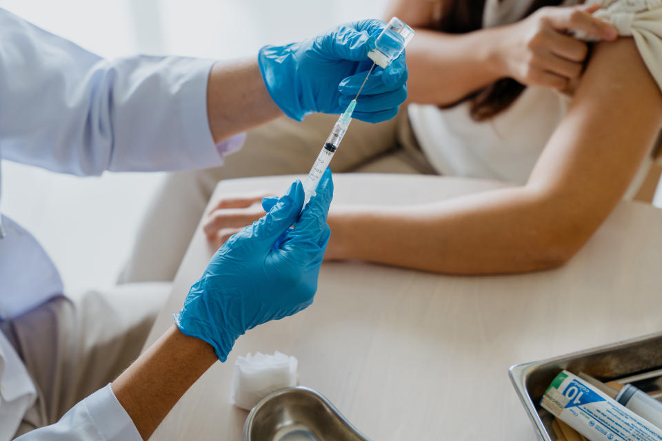 An Asian Chinese woman getting a vaccine injection from her doctor at home. Covid-19 vaccine or flu vaccine injection.