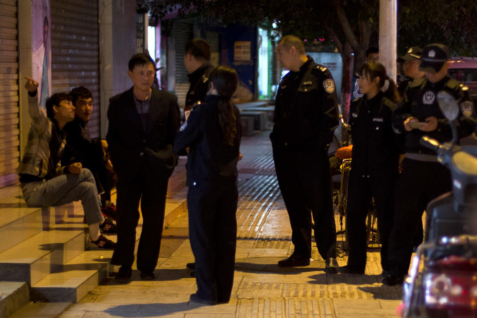 In this Monday March 3, 2014 photo, police officers question two Uighur men, left, as a Han Chinese man walks past them in Kunming, in western China's Yunnan province. China said the vicious slashing spree Saturday that killed 29 people in the southern city was the work of separatists linked to international terrorism, but the assailants’ homespun methods and low-tech weapons - nothing more than long knives - have led some analysts to suspect they didn’t get outside help. (AP Photo/Alexander F. Yuan)