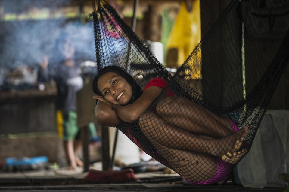 Maijuna youth Arely Riategui smiles while sitting in a hammock inside her home in Sucusari, Peru, Wednesday, May 29, 2024. A federal highway project in an untouched area of the Peruvian Amazon is facing mounting opposition from Indigenous tribes, including the Maijuna. (AP Photo/Rodrigo Abd)