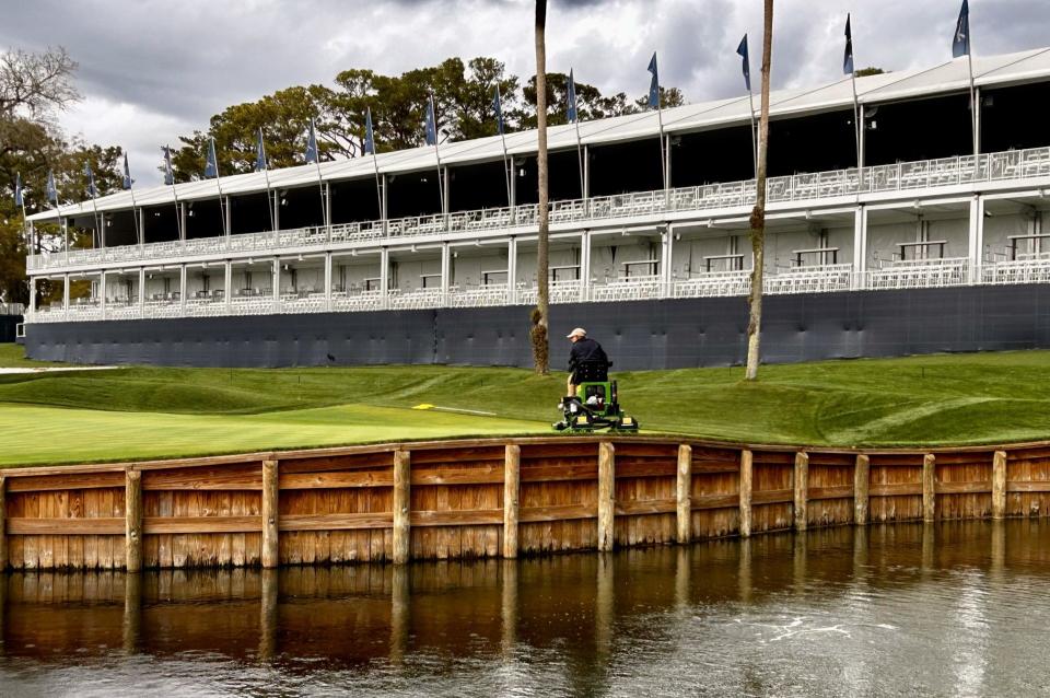 A TPC Sawgrass maintenance worker mows the 16th green of the Players Stadium Course.