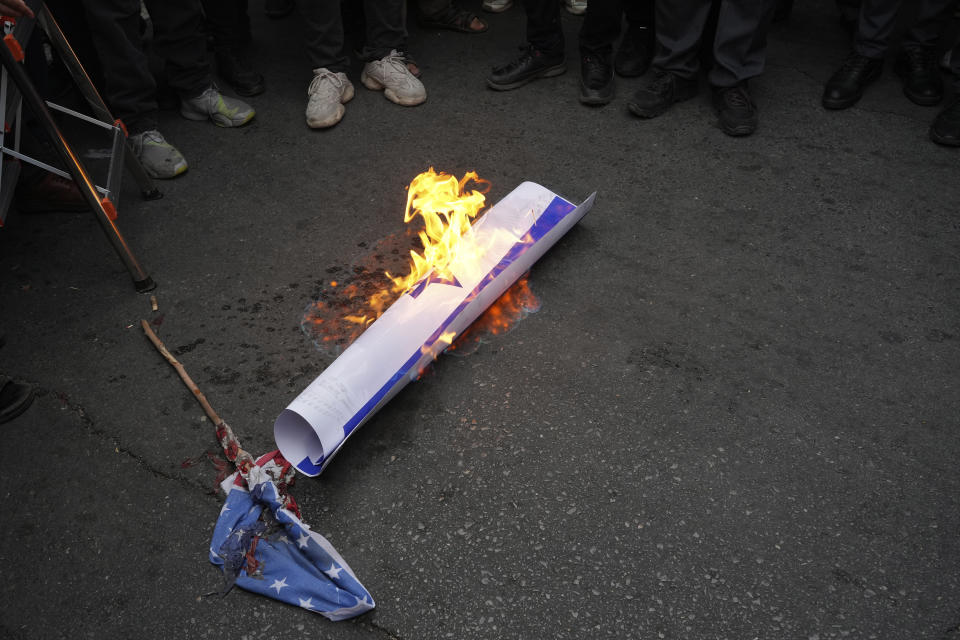 Protesters burn representations of the U.S. and Israel flags during a protest against Sweden in front of the Swedish Embassy in Tehran, Iran, Friday, July 21, 2023. Thousands of people took to the streets in a handful of Muslim-majority countries Friday to express their outrage at the desecration of a copy of the Quran in Sweden, a day after protesters stormed the country's embassy in Iraq. (AP Photo/Vahid Salemi)