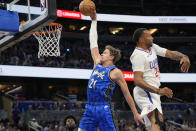 Orlando Magic center Moritz Wagner (21) goes past Los Angeles Clippers guard Norman Powell (24) for a dunk during the first half of an NBA basketball game, Friday, March 29, 2024, in Orlando, Fla. (AP Photo/John Raoux)