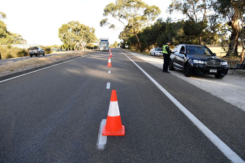 Motorists fill out paperwork for police as they cross back into South Australia from Victoria during the coronavirus disease (COVID-19) outbreak, in Bordertown