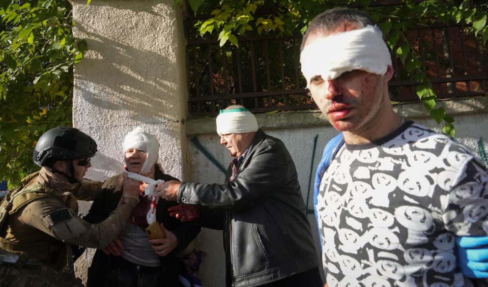 FILE - People receive medical treatment at the scene of Russian shelling, in Kyiv, Ukraine, Monday, Oct. 10, 2022. Ukrainians' resilience in the nearly 8-month-old war continues to be unwavering, despite an uptick in attacks that are seen as Russian President Vladimir Putin's vengeful response to an explosion that damaged a Moscow-built bridge to the Kremlin-annexed Crimean Peninsula on Oct. 8. (AP Photo/Efrem Lukatsky, File)