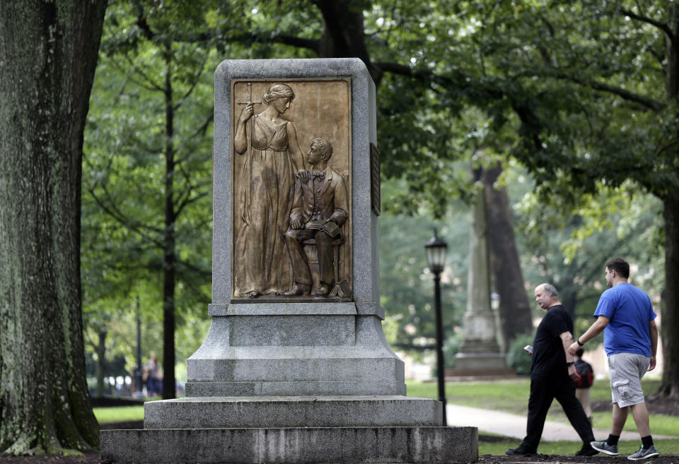 People gather around the remaining monument following a Monday night rally where the Confederate statue known as Silent Sam was toppled from it's pedestal by protesters at the University of North Carolina in Chapel Hill, N.C., Tuesday, Aug. 21, 2018. The bronze figure of a Southern soldier atop a tall stone pedestal was erected by the United Daughters of the Confederacy in 1913.(AP Photo/Gerry Broome)