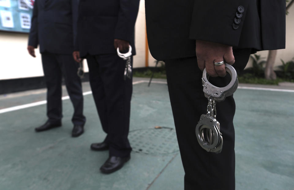 In this July 19, 2019 photo, guards stand by with handcuffs in a prison courtyard in Callao, Peru. Prisoners taking part in classical music sessions are handcuffed before they are transported in an armored bus to the national theater in Lima, the Peruvian capital. (AP Photo/Martin Mejia)