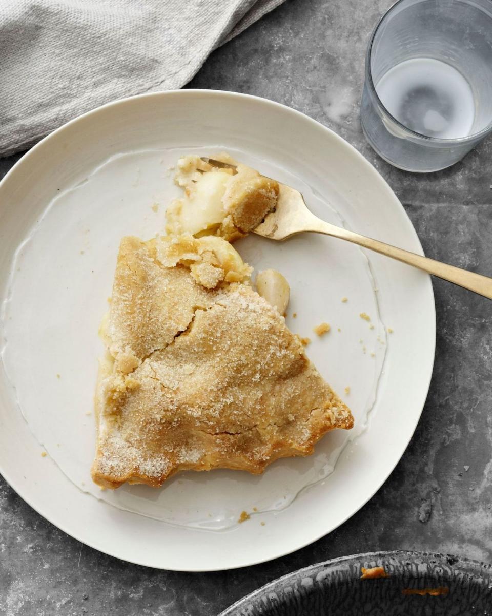 a slice of double crust all american apple pie on a white plate with a gold fork