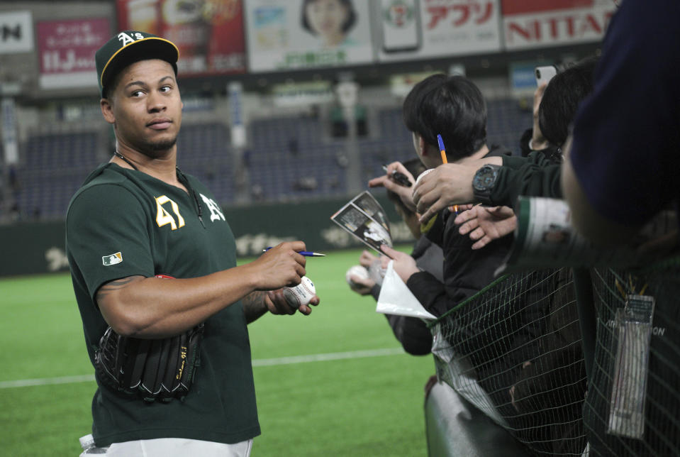 Oakland Athletics pitcher Frankie Montas gives his autograph to fans prior to their pre-season exhibition baseball game against the Nippon Ham Fighters at Tokyo Dome in Tokyo Monday, March 18, 2019. (AP Photo/Eugene Hoshiko)