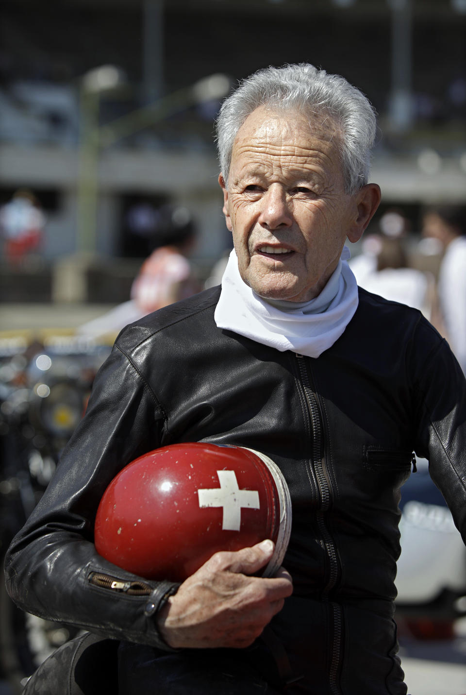 Legendary Swiss motorcycle road racer, three times World Champion in 1962, 1964, and 1966 Luigi Taveri (1929) poses for a photo with his helmet nearby an oval track of a velodrome during an old timer car and motorcycle show in Budapest on May 1, 2012. The event brought life again into the 412 meter long Millennial Velodrome of Budapest, which was built in 1896 and is one of the oldest arenas for track cycling in Europe.  AFP PHOTO / PETER KOHALMIPETER KOHALMI/AFP/GettyImages