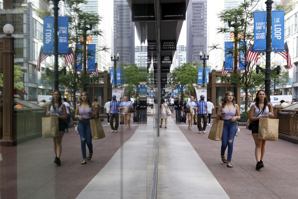 Shoppers are reflected in a retail store's windows, Tuesday, May 25, 2021, in Chicago's famed Loop. With vaccinations rolling out and shoppers freer to go out maskless, retailers are seeing an eager return to their stores after months of watching their customers focus on online buying during the pandemic. (AP Photo/Shafkat Anowar)