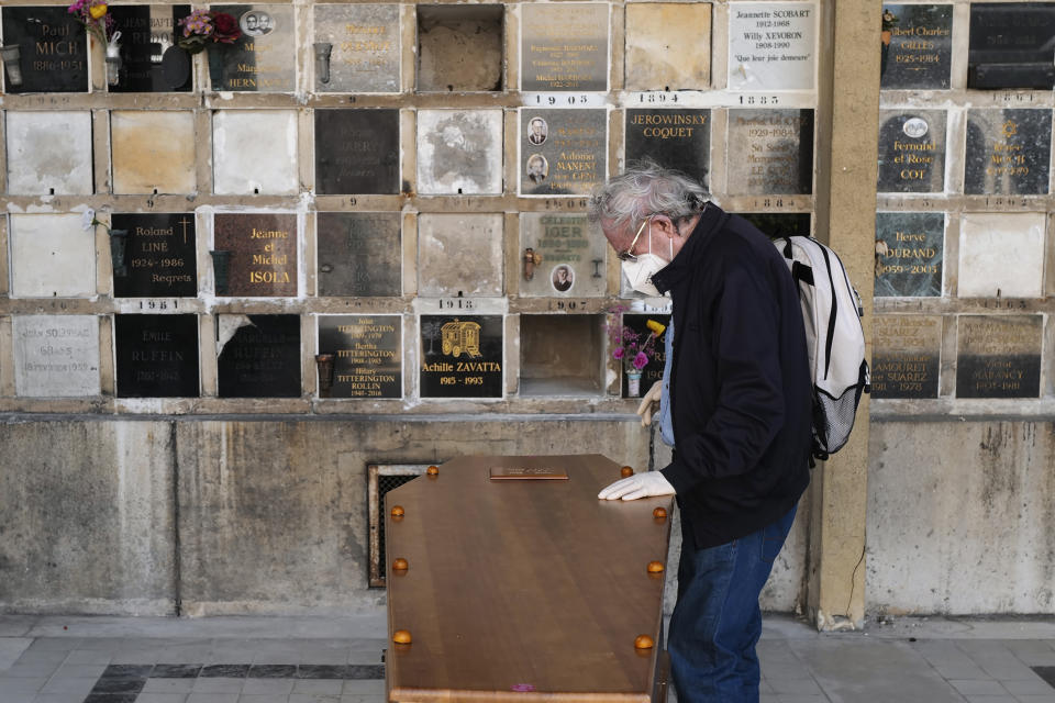 A man pays respect near the coffin of his wife who was 75-years-old, during a funeral ceremony under the care of Paris undertaker Franck Vasseur, at Pere Lachaise cemetery in Paris, Friday, April 24, 2020 as a nationwide confinement continues to counter the COVID-19 virus. (AP Photo/Francois Mori)