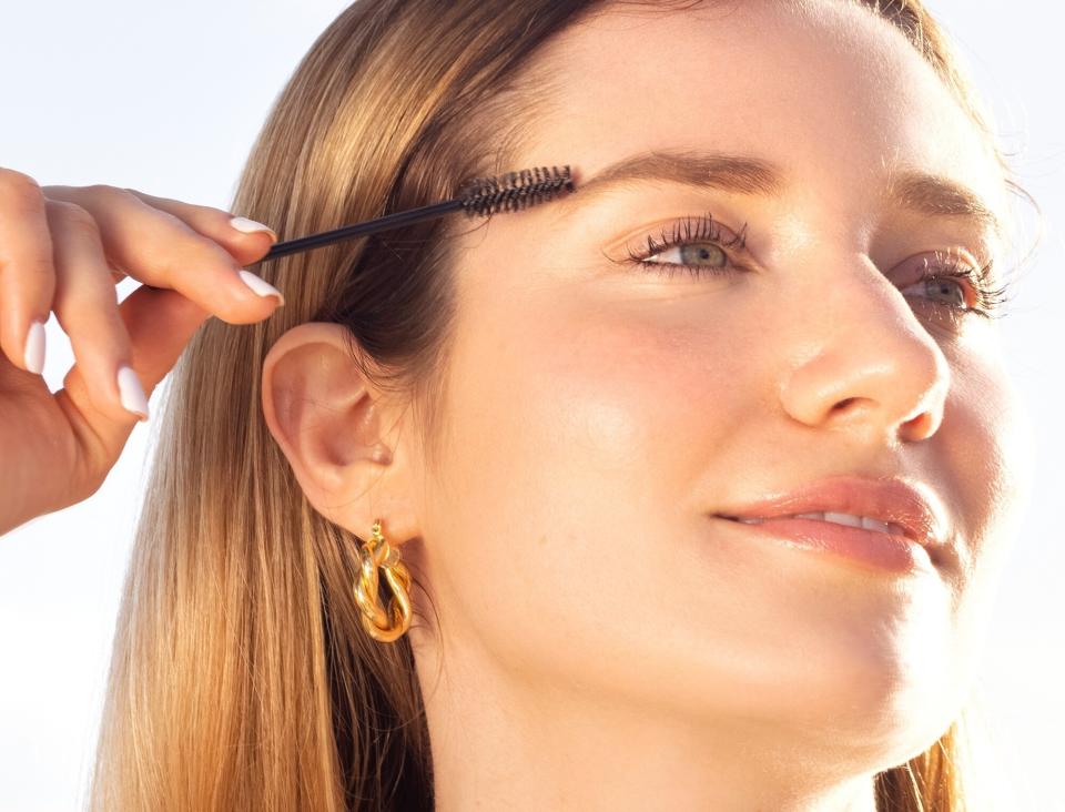 A person applying the serum on their eyebrows