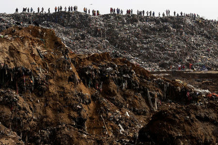 Garbage collectors look at rescue teams (not pictured) working at the site where a massive pile of garbage collapsed at a landfill dumpsite in Guatemala City, Guatemala. REUTERS/Josue Decavele