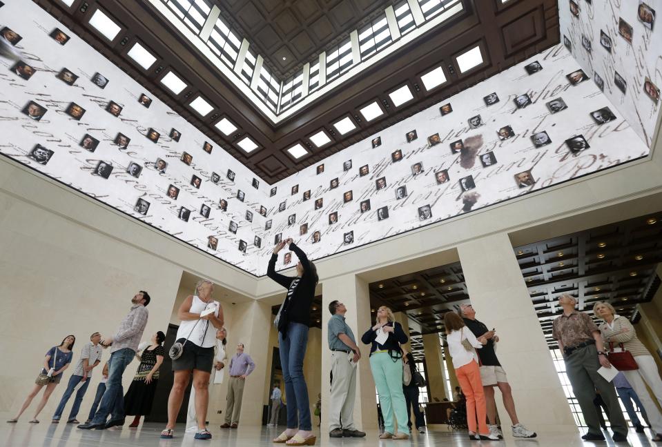 FILE - Visitors to the George W. Bush Presidential Library and Museum look upwards at a 360 degree video screen showing a video welcoming them to the center in Dallas, on May 1, 2013. Concern for U.S. democracy amid deep national polarization has prompted the entities supporting 13 presidential libraries dating back to Herbert Hoover to call for a recommitment to the country's bedrock principles, including the rule of law and respecting a diversity of beliefs. (AP Photo/Tony Gutierrez, File)