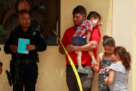 A police officers looks on as people react near a crime scene where the bodies of several people were found inside a house, days before the visit of Mexico's President-Elect Andres Manuel Lopez Obrador, in Ciudad Juarez, Mexico August 3, 2018. REUTERS/Jose Luis Gonzalez