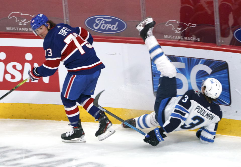 Winnipeg Jets' Tucker Poolman, right, falls after taking a hit from Montreal Canadiens' Tyler Toffoli during second-period NHL hockey game action in Montreal, Thursday, March 4, 2021. (Paul Chiasson/The Canadian Press via AP)