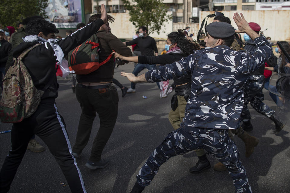 Riot police and army soldiers scuffle with anti-government protesters outside a military court in Beirut, Lebanon, Monday, Feb. 8, 2021. Riot police briefly clashed Monday in Beirut with hundreds of protesters demanding the release of anti-government activists detained following riots in northern Lebanon late last month. (AP Photo/Hassan Ammar)