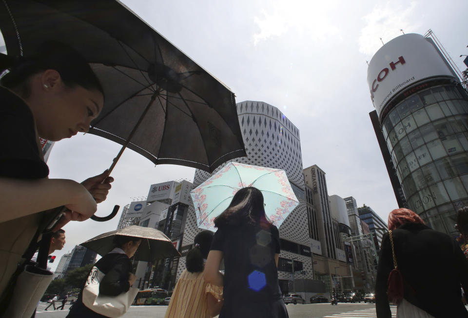 <p>People shade themselves from the heat of the sun with umbrellas as they pass the Ginza shopping district in Tokyo, July 23, 2018. (Photo: Koji Sasahara/AP) </p>