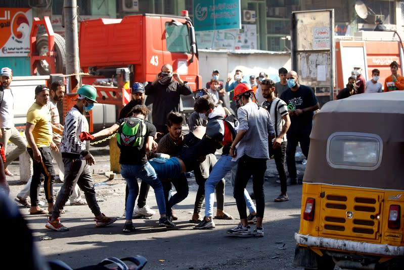 Demonstrators carry a wounded man during the ongoing anti-government protests in Baghdad