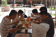 A group of five people have lunch together at the Newton Food Center Friday, June 19, 2020, in Singapore. Singaporeans can now wine and dine at restaurants, work out at gyms and get together with five people or less after most lockdown restrictions were lifted Friday. (AP Photo/YK Chan)