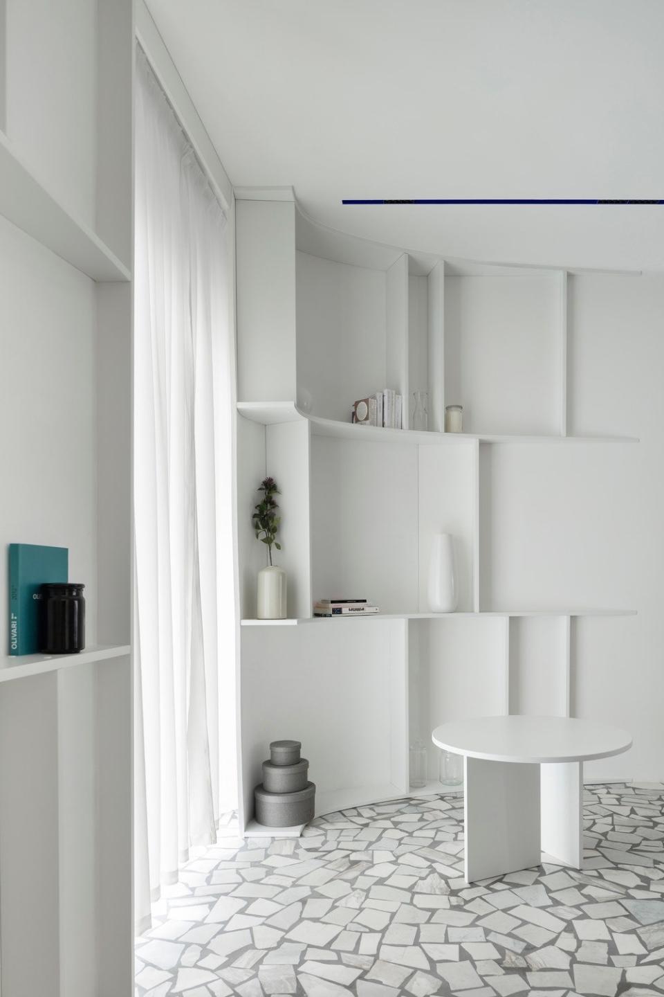 All of the walls and furniture were custom made, from the shelving to the all-white side tables.