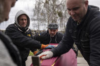 Vlad Minchenko, center, helps to close the coffin of Stanislav Berestnev who died during the Russian occupation and was buried in the graveyard in Bucha, Ukraine, Tuesday, April 19, 2022. Minchenko wakes every day with trembling hands. For hours, until it eases, he can't message on his phone or even consider his previous work of making art or tattoos. But he can continue to retrieve bodies, scores of bodies, around the Ukrainian town of Bucha as part of a task that continues more than three weeks after Russian forces withdrew.(AP Photo/Evgeniy Maloletka)