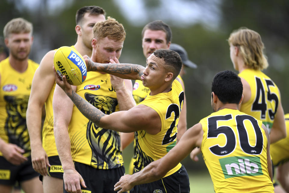 Richmond Tigers' Shai Bolton, center and teammates work out during a training at Metricon Stadium, in Gold Coast, Thursday, Oct. 22, 2020. The Australian Football League will have its grand final on Saturday at Brisbane in the so-called Sunshine State, ending more than a century of tradition. It has been moved from its regular home at the 100,000-capacity Melbourne Cricket Ground because of a coronavirus pandemic spike in Victoria state, where the top-flight grand final has been staged ever since the game of Aussie rules was invented. The Richmond Tigers play the Geelong Cats in Saturday's grand final. (Dave Hunt/AAP Image via AP)