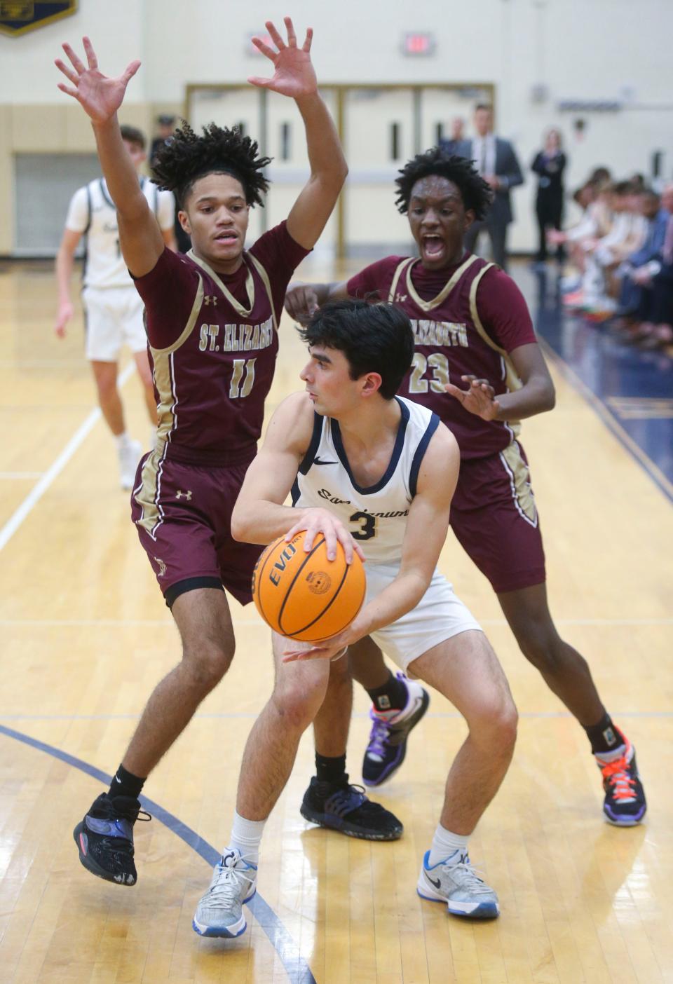 St. Elizabeth's Justin Lawrence (left) and Julius Wright (right) defend against Salesianum's Brendon Baffone in the first half of the Vikings' 54-45 win at Salesianum Friday, Jan. 6, 2023.