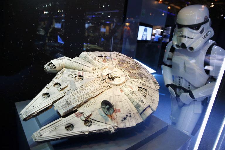 A performer dressed as a stormtrooper character (R) looks at a model of the Millenium Falcon starship from the Star Wars film series, at the Cite du Cinema in Saint-Denis, outside Paris, on February 13, 2014