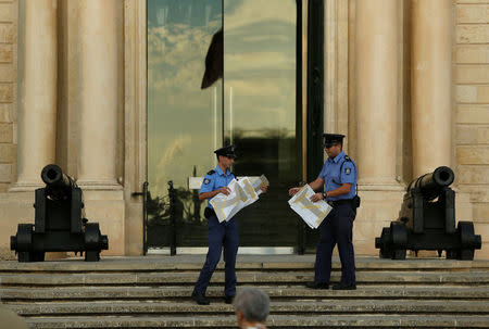 Policemen remove posters calling for government action, left after a silent protest by students, following the assassination of the investigative journalist Daphne Caruana Galizia in a car bomb attack three days ago, on the steps of the office of the Prime Minister at Auberge de Castille in Valletta, Malta, October 19, 2017. REUTERS/Darrin Zammit Lupi