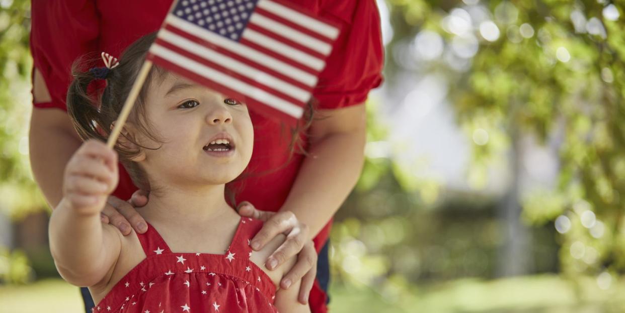 4th of july activities  mother and daughter waving american flags outdoors