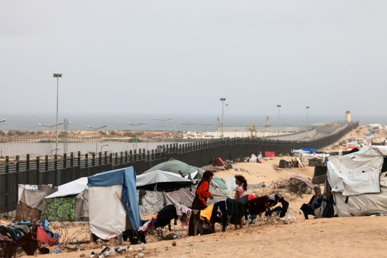 Unos palestinos se sientan fuera de las tiendas de un campamento de desplazados en Rafah, en el sur de la Franja de Gaza, cerca de la frontera con Egipto, para escapar del sofocante calor en su interior el 26 de abril de 2024 (Mohammed Abed)