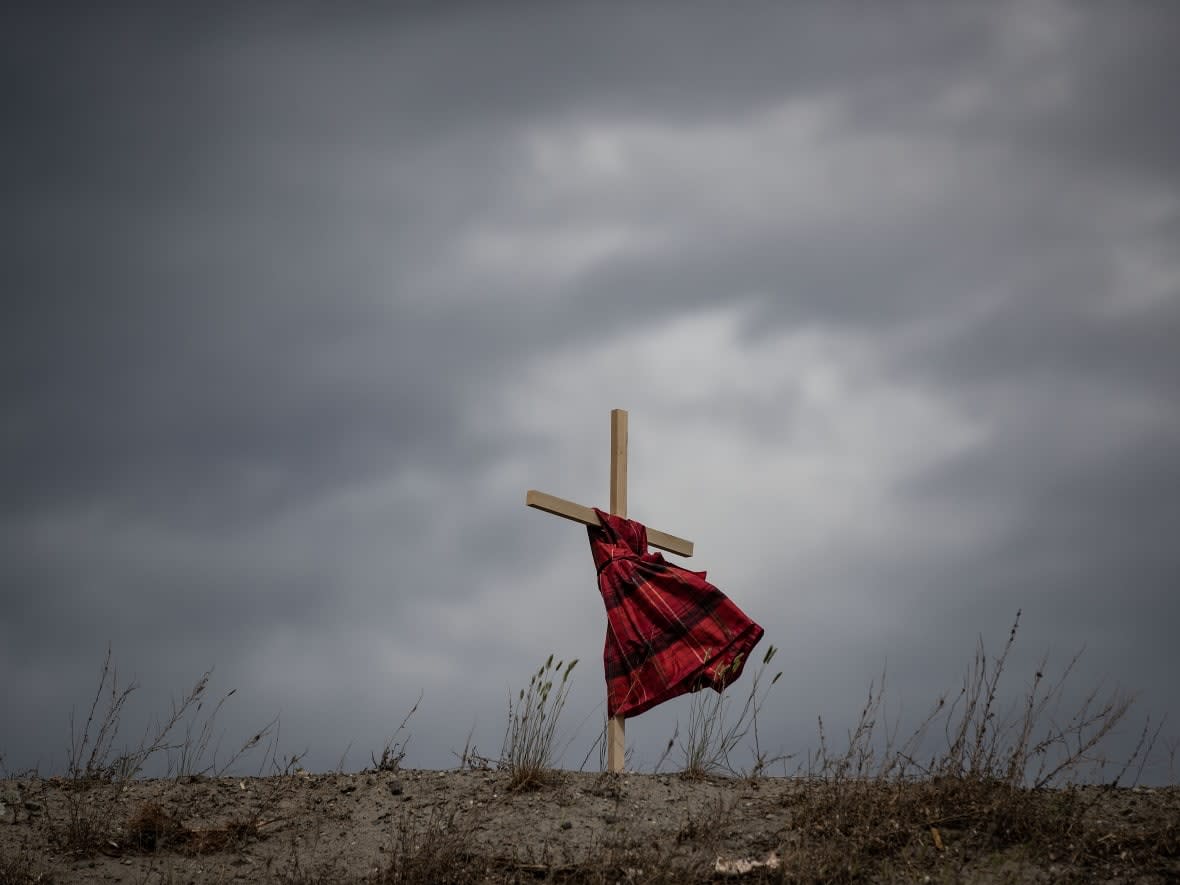 A child's dress hangs on a cross near the former Kamloops Indian Residential School. (Canadian Press/Darryl Dyck - image credit)