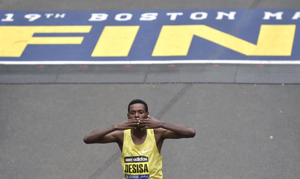 Lelisa Desisa, of Ethiopia, kisses his hands after crossing the finish line to win the men's division of the 119th Boston Marathon in Boston