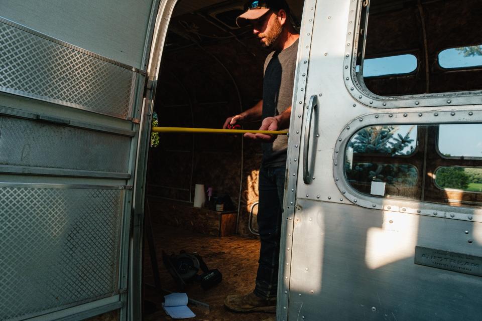 Craig Poole is taking measurements while working to convert a 1973 AirStream trailer into a boutique located on his property in Warren Township. The boutique is planned to be an addition to Sasha Poole's current business at their homestead, The Mod Chair Cosmetic Parlour. Craig plans to make the boutique handicap-accessible.