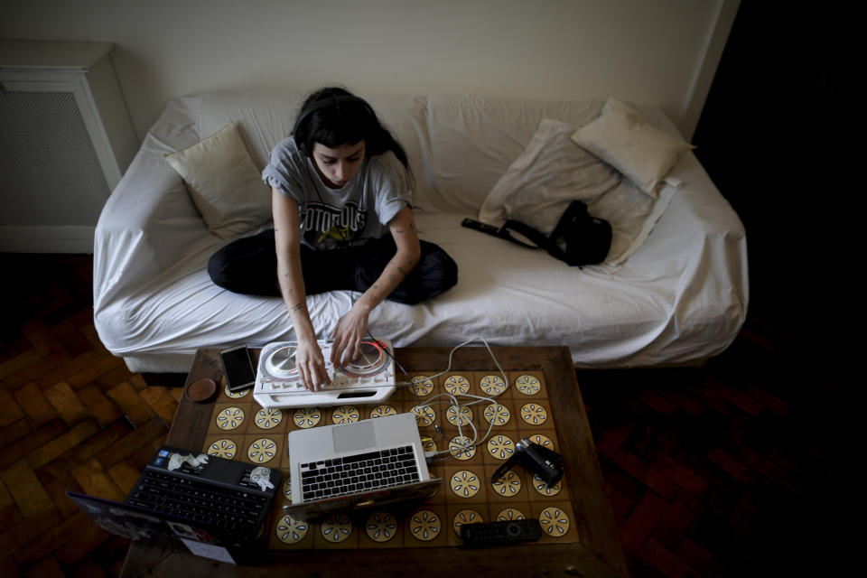 Deflina Espina plays music at home during a government-ordered lockdown to curb the spread of the new coronavirus in Buenos Aires, Argentina, Tuesday, June 30, 2020. Although Espina normally works as a DJ at parties and loves contact with people, she says the quarantine has helped her work on herself. (AP Photo/Natacha Pisarenko)