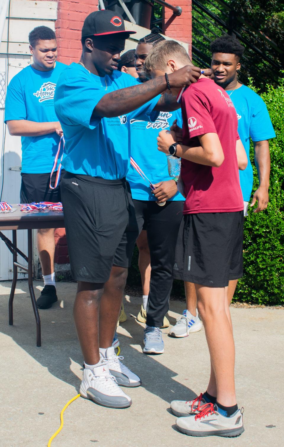 Kansas football player Kenny Logan Jr. awards a medal during the 5K Home Run supporting Family Promise of Lawrence.