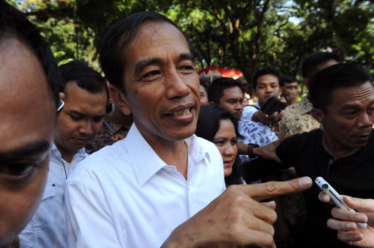 Jakarta Governor Joko Widodo (L), presidential candidate of the opposition Indonesian Democratic Party of Struggle (PDI-P), speaks to journalists after voting at a polling centre in Jakarta on April 9, 2014