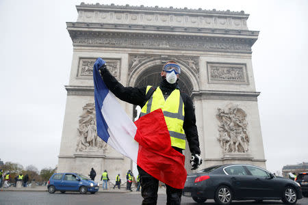 A man waves a French flag near the Arc de Triomphe as protesters wearing yellow vests, a symbol of a French drivers' protest against higher diesel taxes, demonstrate in Paris, France, December 1, 2018. REUTERS/Stephane Mahe