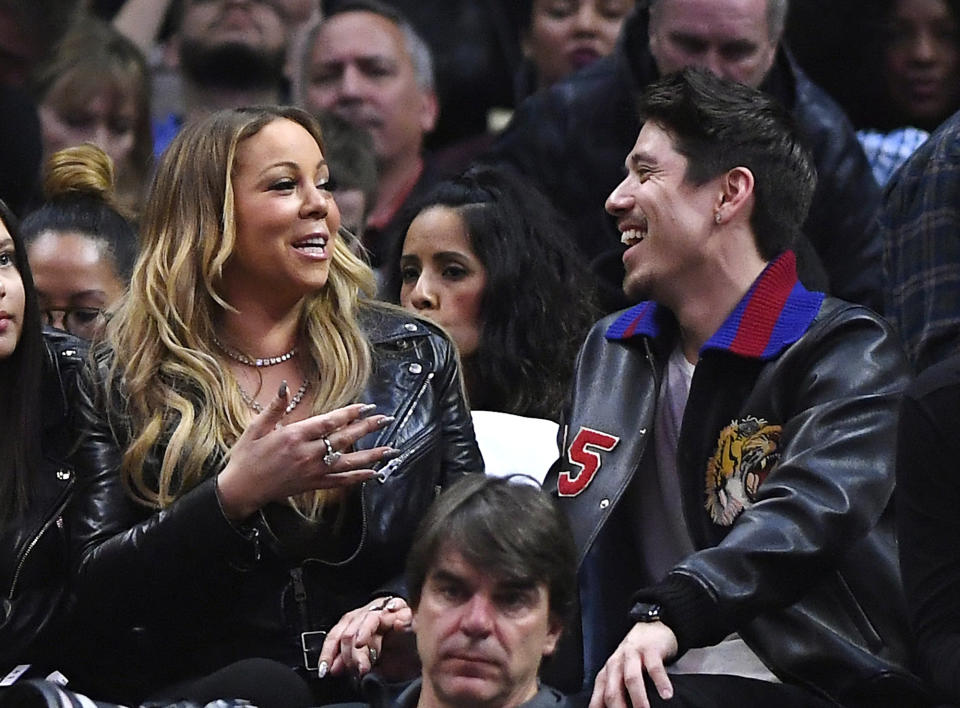 FILE - Singer Mariah Carey, left, talks with Bryan Tanaka during the second half of an NBA basketball game between the Los Angeles Clippers and the Atlanta Hawks, Feb. 15, 2017, in Los Angeles. Carey and Tanaka have split after 7 years together, Tanaka has confirmed. In a statement shared with the Associated Press and published to Tanaka's Instagram on Tuesday, Dec. 26, 2023, Carey's backup dancer-turned-creative director and partner detailed their breakup. (AP Photo/Mark J. Terrill, File)