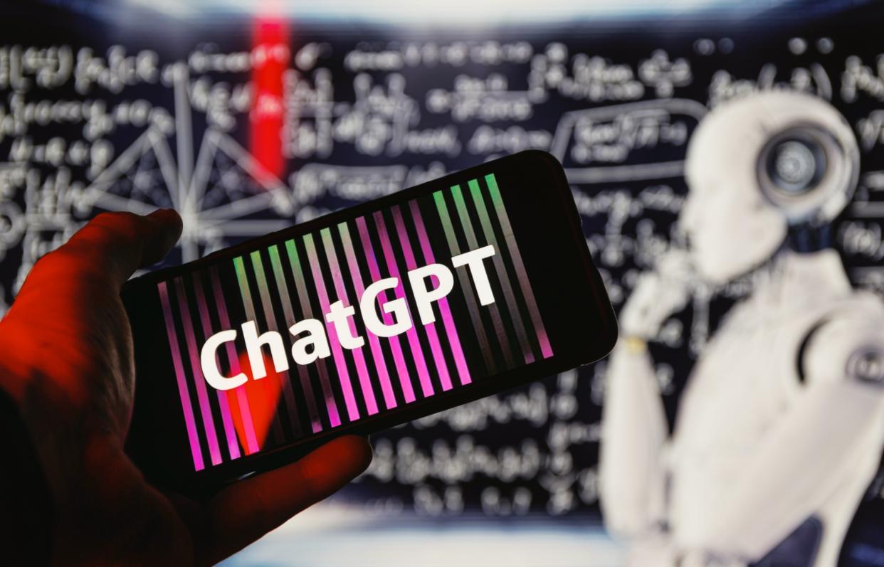  ChatGPT logo on phone in front of robot thinking. 