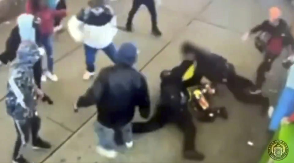 This image taken from video provided by the New York City Police Department shows police officers confronting a group near New York's Times Square, Jan. 27, 2024, bringing a man in a bright yellow coat down to the sidewalk and the chaotic scene that unfolds as at least half a dozen bystanders are seen kicking at the officers, then trying to pry them off the man. (New York City Police Department via AP)