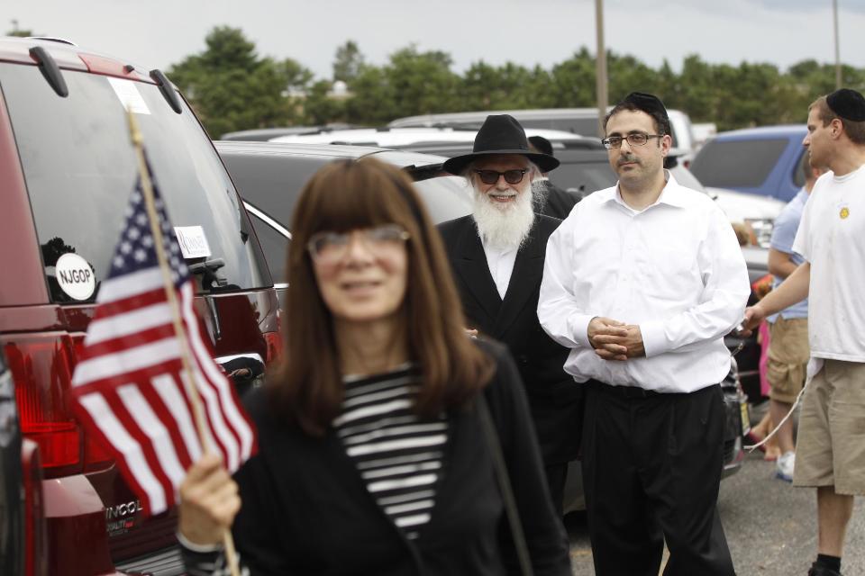 Members of a Jewish wedding party react as the motorcade of Republican presidential candidate and former Massachusetts Gov. Mitt Romney drives past for a campaign fundraising event in Lakewood, N.J., Wednesday, Aug. 8, 2012. (AP Photo/Charles Dharapak)