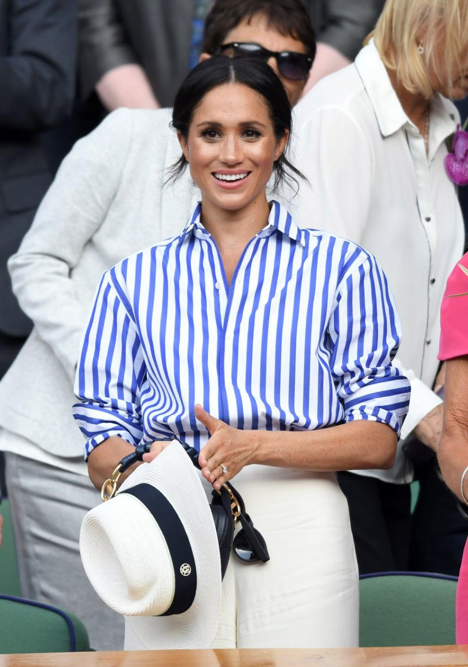 <p>The newlywed wore a classic blue-striped button-down shirt and crisp white wide-leg trousers from Ralph Lauren to Wimbledon, July 2018. </p>