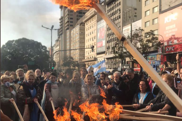 Un grupo de personas con antorchas prendidas frente al obelisco.