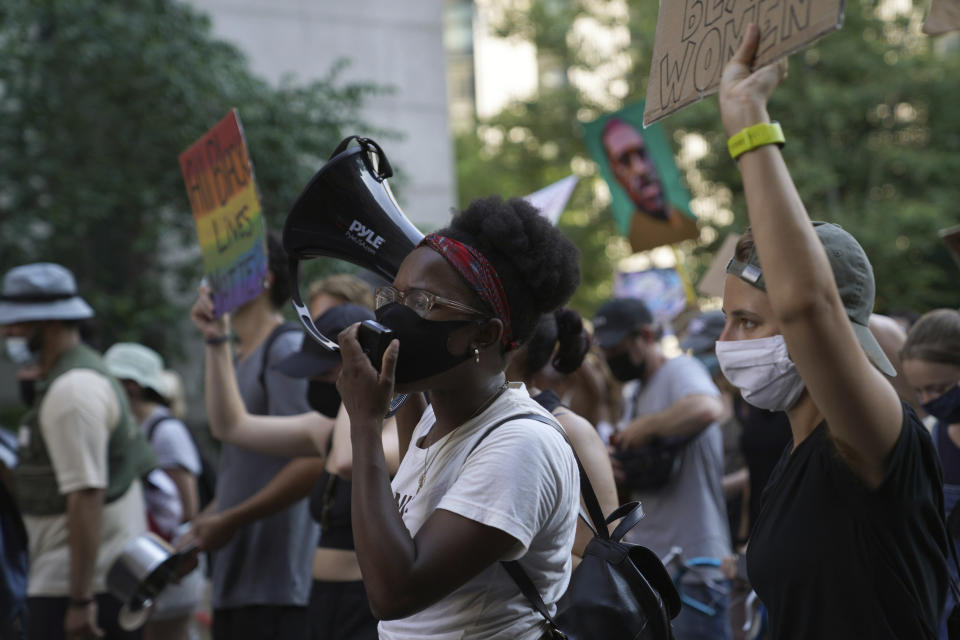 CORRECTS FIRST NAME TO ERIN FROM ERIC - Kianna Ruff, left, and Erin Hancock, right, two activists who met in seminary, protest against racial injustice and police brutality July 26, 2020, in Manhattan, New York. Many involved in the demonstrations that erupted after George Floyd's killing say they deepen spiritual connections and embody familiar elements of traditional faith. (AP Photo/Emily Leshner)