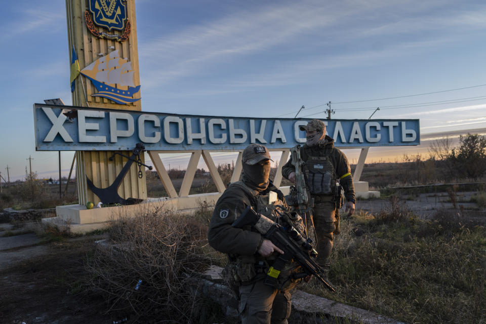 FILE - Two Ukrainian defence forces members stand next to a sign reading "Kherson region" in the outskirts of Kherson, southern Ukraine, Nov. 14, 2022. Even as Ukraine celebrates recent battlefield victories, its government faces a looming challenge on the financial front: how to pay the enormous cost of the war effort without triggering out-of-control price spikes for ordinary people or piling up debt that could hamper postwar reconstruction. (AP Photo/Bernat Armangue, File)