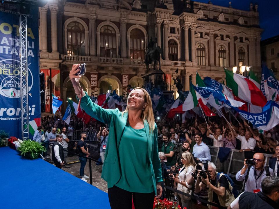 Giorgia Meloni takes a selfie with supporters during a rally.