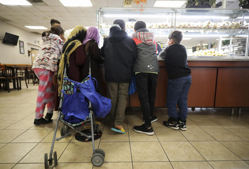 Afghan refugee children wait for a serving of yogurt and honey during the lunch hour at a dining facility in Liberty Village on Joint Base McGuire-Dix- Lakehurst in Trenton, N.J., Thursday, Dec. 2, 2021. (Barbara Davidson/Pool via AP)